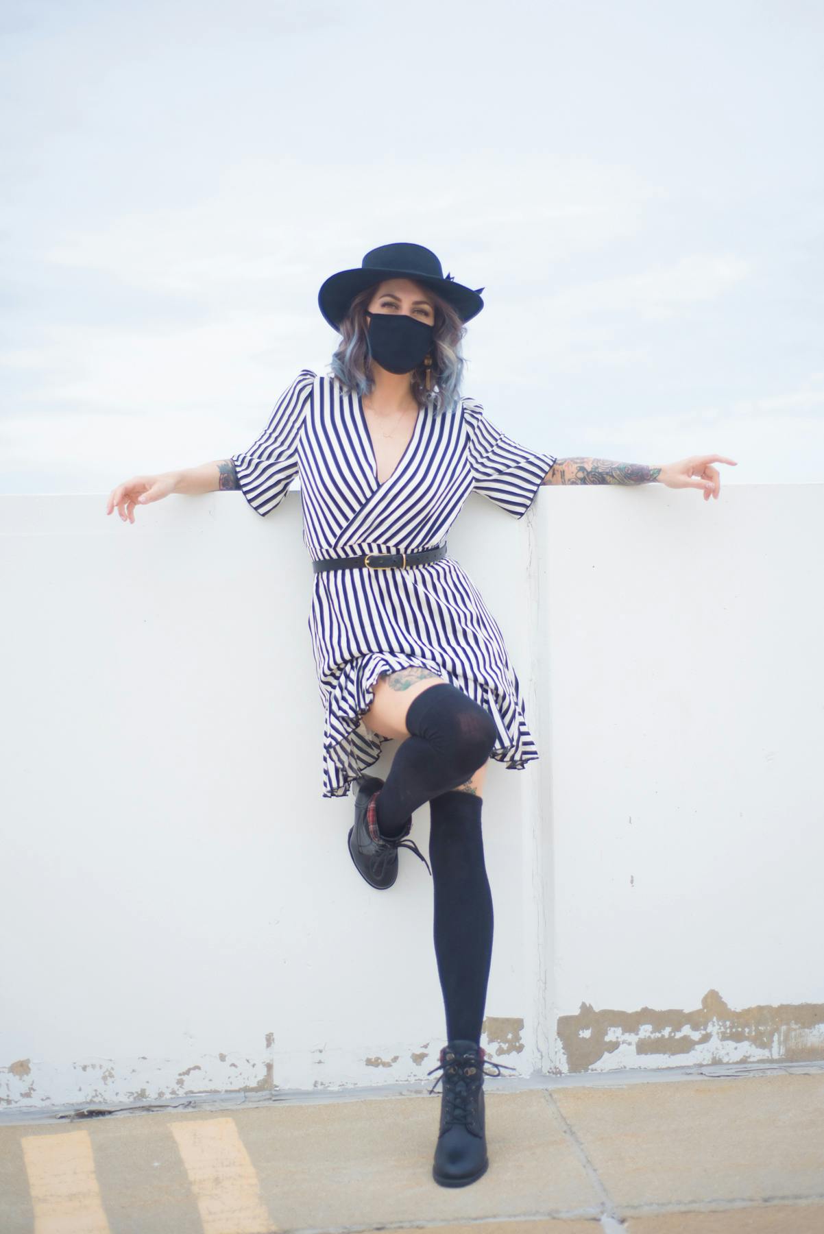 a portrait of Christina wearing a striped dress, knee high black socks and black mask and hat.