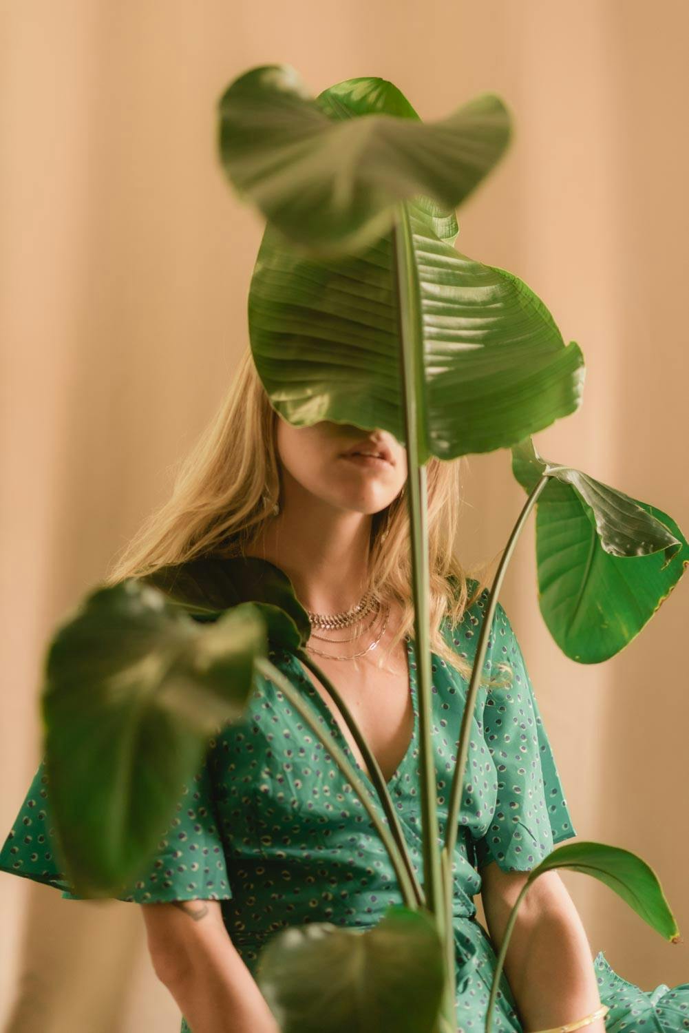 a portrait of Amanda with one of her plants covering her face partially.